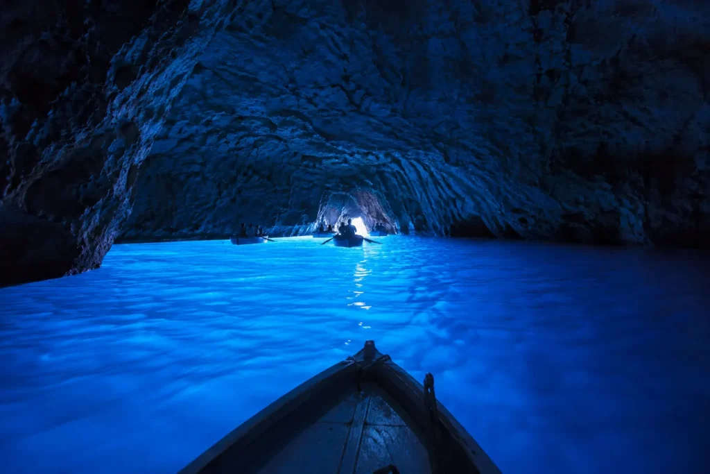 Blue Grotto in Capri with glowing blue water and traditional boats inside the sea cave